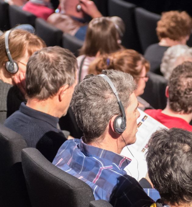 Blinde en slecht ziende bezoekers met audiodescriptie op de koptelefoons bij operavoorstelling.